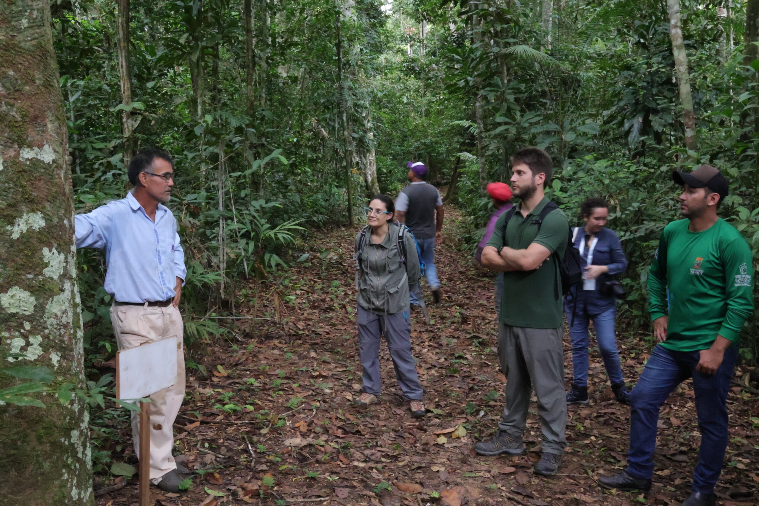Dom Manuel explains the different economic cycles the region went through next to a rubber tree. Photo by the ACEAA.