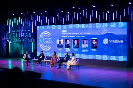 People on a stage in front of a large screen that says Clima Carbono Brasil