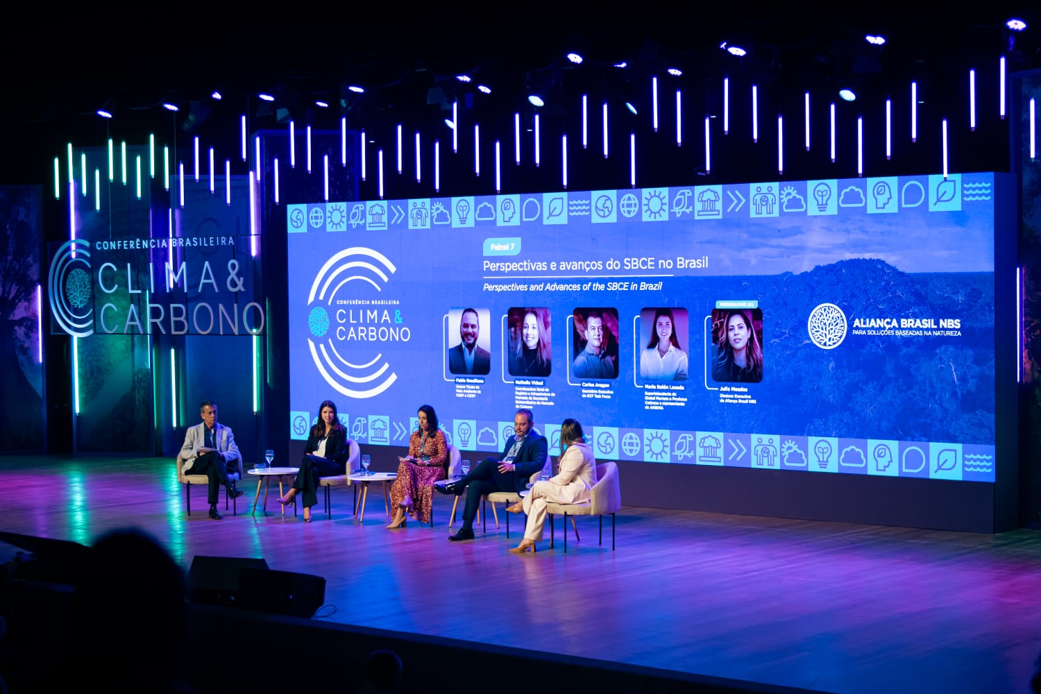 People on a stage in front of a large screen that says Clima Carbono Brasil